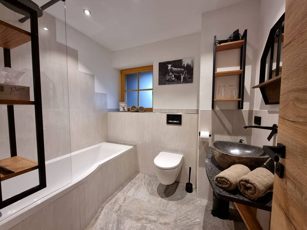 Großes Badezimmer mit Badewanne, WC und Steinwaschbecken_Alm Chalet