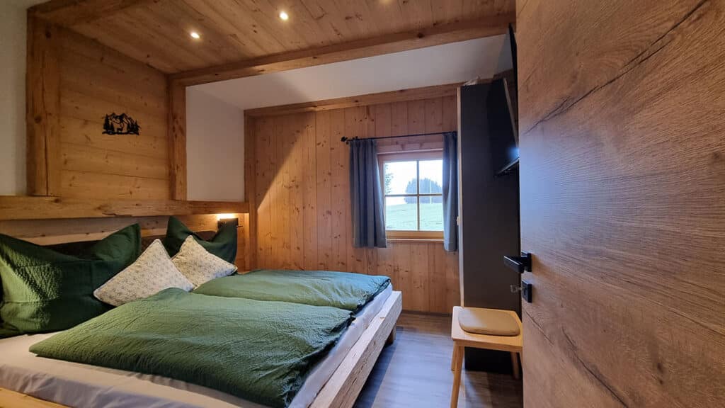 Schlafzimmer Nr. 1 mit Massivholzbett und Holzverkleidung_Alm Chalet